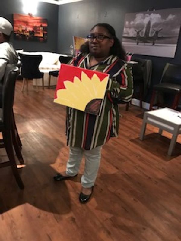 A guest holding a sunflower painting